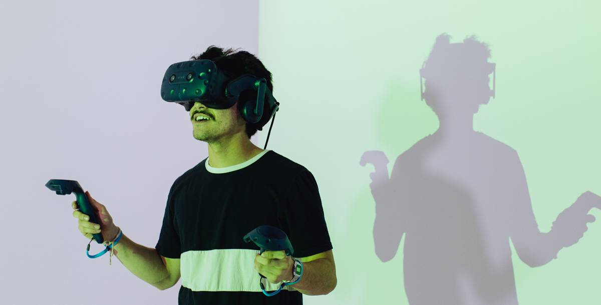 Man wearing a VR headset and headphones holding VR game controllers in each hand